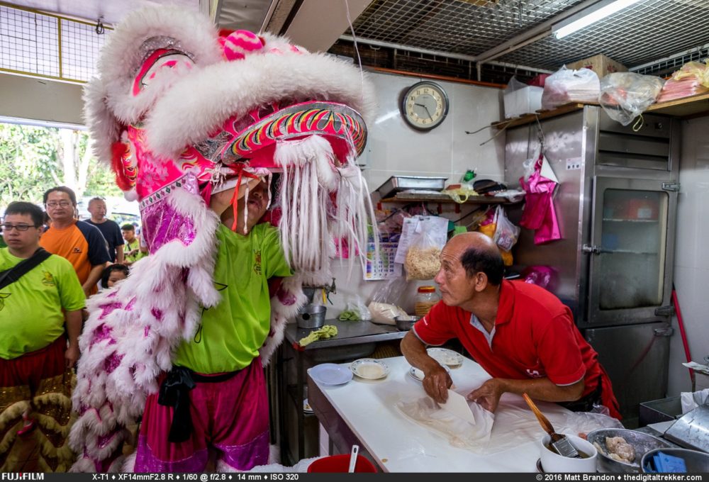 Albert, the Chee Cheong Fun hawker, sneaks a peak at the man behind the lion mask.